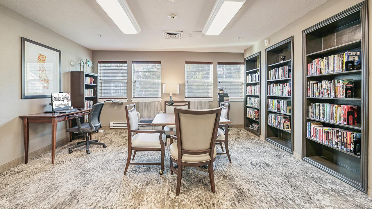 The library at Camden Springs with shelves of books and comfortable seating